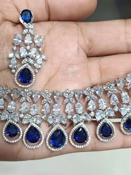 A classic American Diamond necklace set with deep blue sapphire-like stones. The teardrop design is timeless and elegant, making it a versatile addition to your party wear collection.