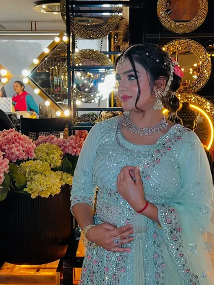 A beautiful candid-style photo. The soft pink and yellow flowers in the background complement the pastel colors of the outfit and the floral accessories in the model's hair.