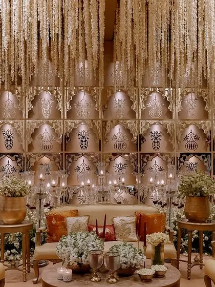 This spectacular backdrop was created with a wall of backlit jaali panels and a ceiling of hanging jasmine strings. The design is a modern interpretation of traditional Indian architectural elements.