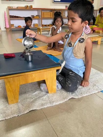 Pouring water from one jug to another is a classic Montessori practical life exercise. It requires immense focus and control, helping the child refine their hand-eye coordination and develop a steady hand.