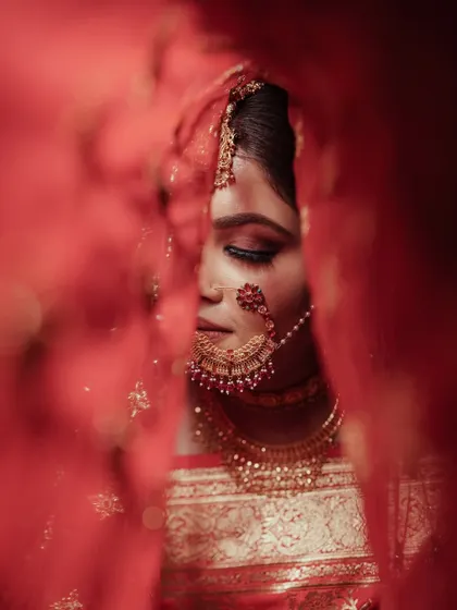 A bridal portrait is more than a photo; it's a story. Here, we created an artistic and intimate moment with our bride Kriti, using her vibrant red veil to frame her serene expression just before the ceremony began.