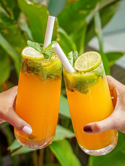 A "cheers" moment with two mango mojitos against a lush green background. This lifestyle shot evokes feelings of vacation and relaxation.