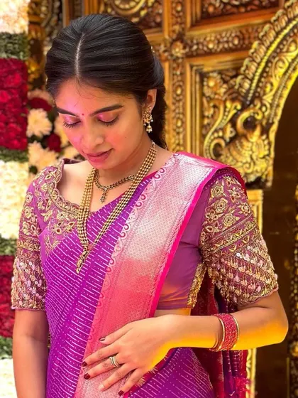 The client looking down, showcasing the detailed embroidery on the sleeves of her purple blouse and her traditional jewelry.
