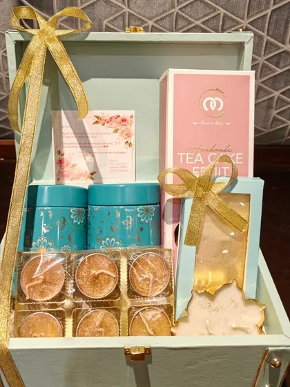 An open view of my popular trunk hamper, curated for a corporate Diwali order. It includes two tea tins, a handmade fruit cake, and a set of six decorative diyas, all elegantly arranged.