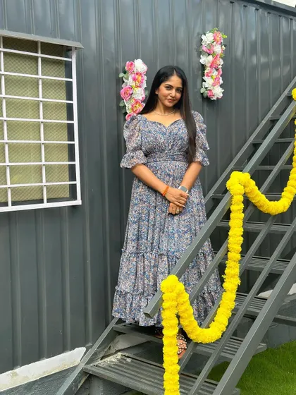 The client on a staircase, showing the full length and flow of her custom floral dress.