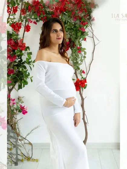 A thoughtful and glowing portrait of an expecting mother. The soft light and floral background create a dreamy and peaceful atmosphere.