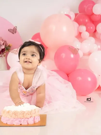 A happy glance up at the balloons. Capturing these spontaneous, joyful expressions is what makes first birthday photoshoots so special.