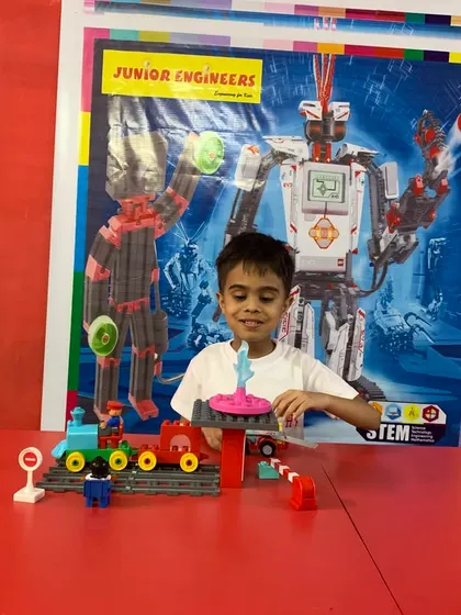 One of our youngest students enjoys building a colorful train set, developing foundational skills through play.