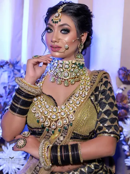 A three-quarter portrait of the bride against a floral background. The combination of the black and gold outfit with the heavy jewellery creates a look of pure opulence.