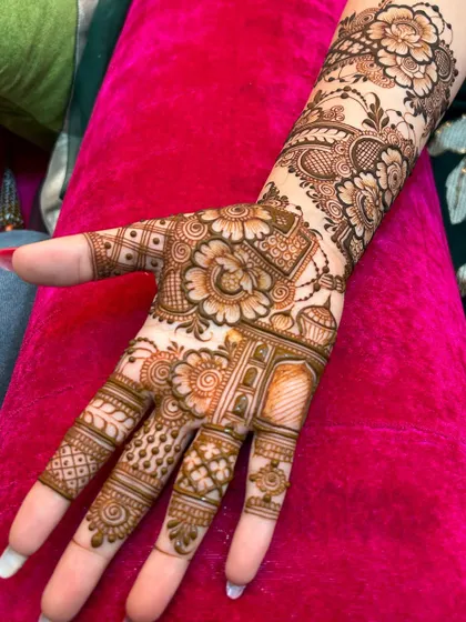 A close-up of a single hand adorned with a rich fusion design. It includes floral elements, an architectural dome, and various traditional fillers for a complete look.