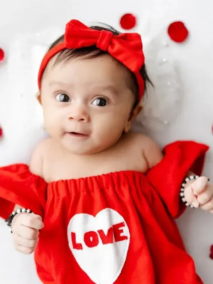 A sweet, wide-eyed baby ready to celebrate her first Valentine's Day.