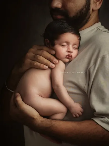 A newborn sleeps peacefully on their father's chest. This fine art portrait captures the warmth, safety, and deep bond in this tender moment.