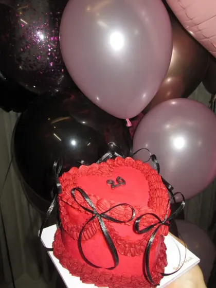 Our red and black vintage heart cake, pictured with party balloons, ready to be the centerpiece of a stylish birthday party.