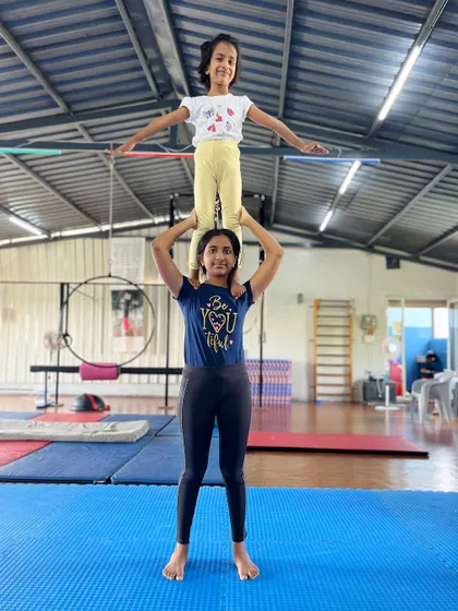 A perfect demonstration of a stable and confident partner balance. The flyer holds a bar to help with stability as they build their skills.