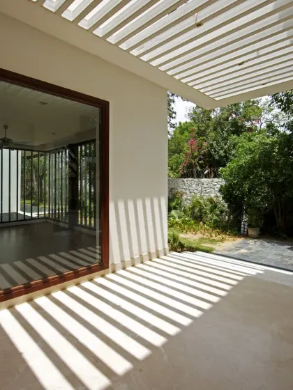 The pergola at Sachdeva Farmhouse casts bold, shifting shadows throughout the day. This dynamic play of light transforms a simple transitional zone into an engaging visual experience, blurring the boundary between inside and outside.