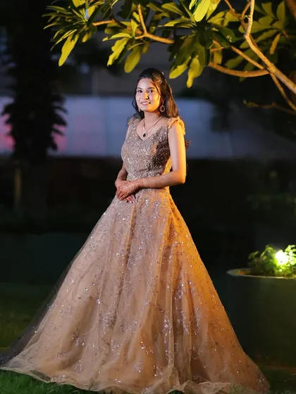 A full-length portrait showing the flow and sparkle of the gown. The makeup enhances her features without overpowering the look.