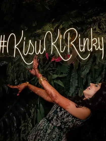 A bride having fun posing with her custom neon hashtag sign, a detail we love to incorporate.