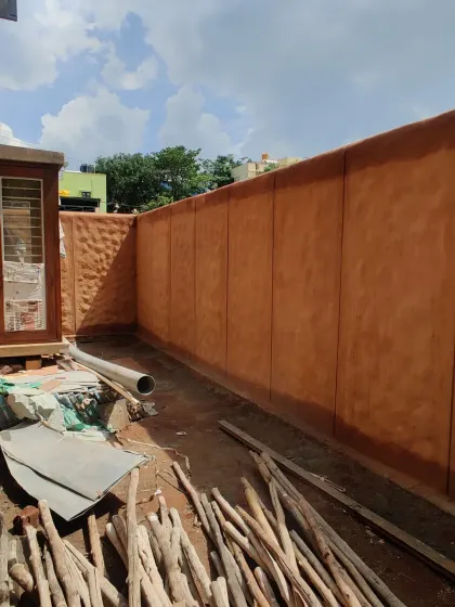 A textured mud compound wall under construction.
