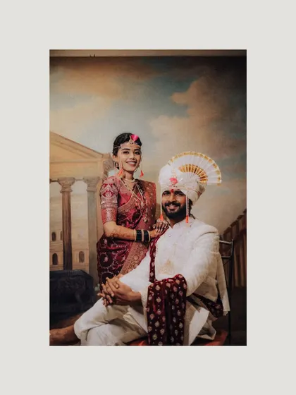A formal portrait of a Maharashtrian couple against a classic painted backdrop. This photo has a timeless, almost royal quality, celebrating their heritage.