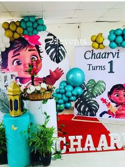A tropical Moana theme for a first birthday, using teal and gold balloons and leafy green elements.