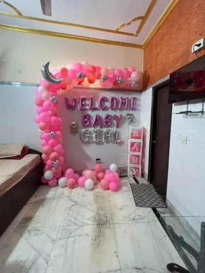 A wider perspective of the pink 'Welcome Baby Girl' setup, showing how it fits into the corner of a room next to a daybed.