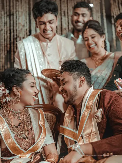 A candid moment during a wedding ritual, filled with laughter from the couple and their family. These are the real, unposed memories that tell the best stories.