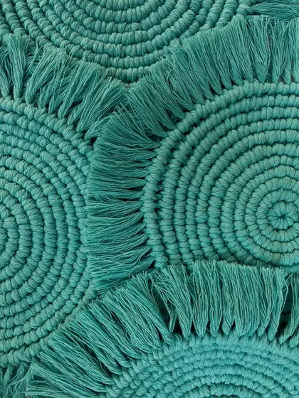 A close-up shot of the turquoise coasters, highlighting the tight, consistent knotting. This view shows the texture and craftsmanship that goes into each small piece.