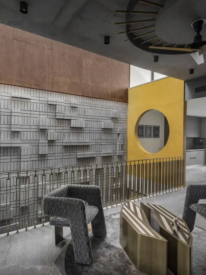 The triple-height atrium in Swatantra Residence is a juxtaposition of textures. The rustic patina of corten steel contrasts with the roughness of concrete, while a pigmented yellow cutout elevates the interior design to the level of art.