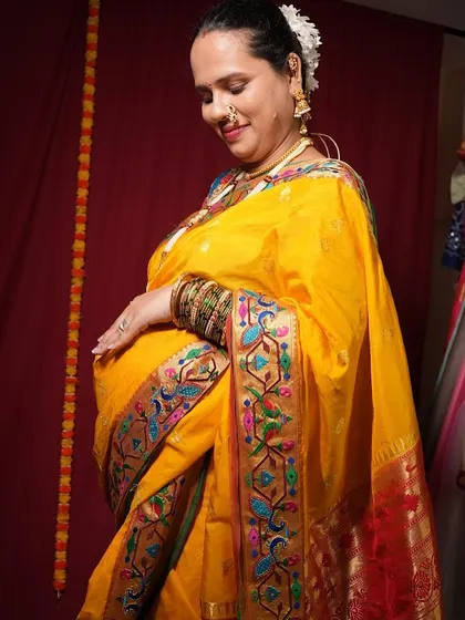 The intricate border of the Paithani saree is the highlight of this traditional maternity look.