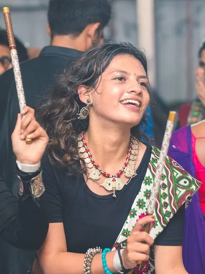A smiling guest enjoying the dandiya night. My goal is to create a fun and inclusive atmosphere where everyone feels comfortable dancing.
