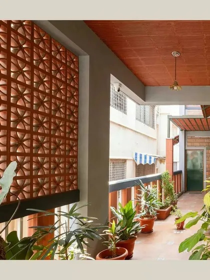 A terracotta jaali screen provides privacy for this elevated verandah while allowing light and air to filter through. This creates a comfortable, semi-outdoor living space that connects the home to the neighborhood.