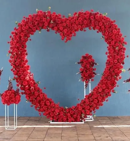 A large, heart-shaped floral arch made entirely of red roses. This makes a stunning photo backdrop for a Valentine's Day corporate event or any celebration of love and appreciation.