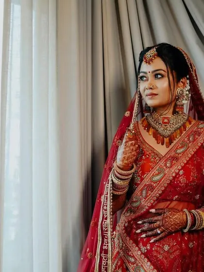 A classic bridal portrait by the window. The bride's gaze is directed outside, creating a sense of anticipation and wonder, beautifully lit by natural light.
