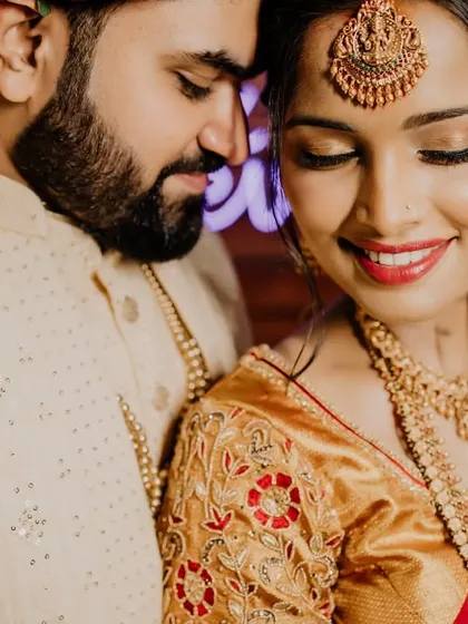 A close-up, intimate portrait of a South Indian couple. The bride's smile and the groom's gentle gaze create a moment of pure, serene love.