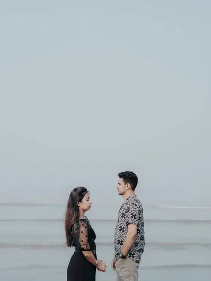 A symmetrical and powerful pose of the couple facing each other against the vastness of the sea and sky.