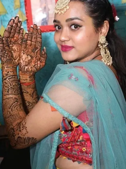 A happy bride posing with her full bridal mehndi. The design is a beautiful mix of traditional patterns and personalized elements.