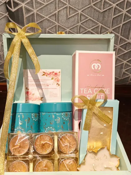 This is my exclusive trunk box, a popular choice for premium corporate gifting. This particular curation includes a handmade tea cake, decorative tins, and a set of floating candles.