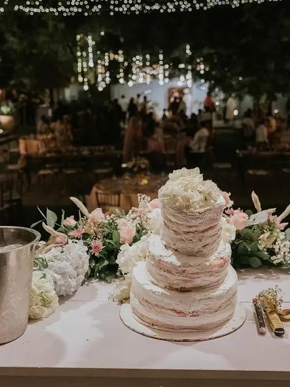 A beautiful tiered wedding cake and champagne ready for the reception, set against the backdrop of our venue lit up at night.