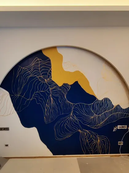 Abstract art allows for a unique expression of mood and style. This piece, set within a grand arch in a luxury bedroom, uses bold strokes of blue, ochre, and delicate gold linework to create a dramatic and sophisticated accent wall.