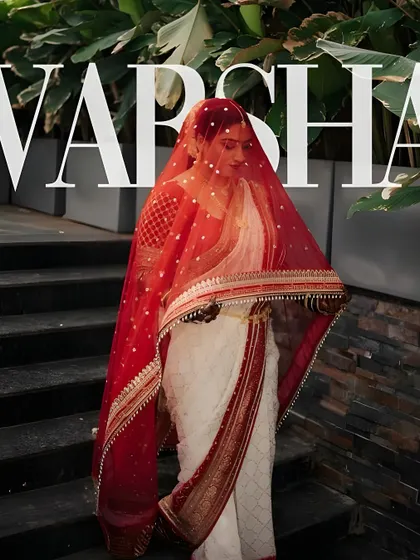 An editorial bridal shot that captures a sense of mystery and elegance. The makeup is bold yet refined, with a flawless base that glows even from under the delicate red veil, creating a powerful and memorable image.