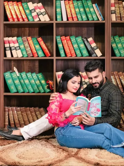 A couple shares a quiet moment reading a book together in a library setting during their pre-wedding shoot.