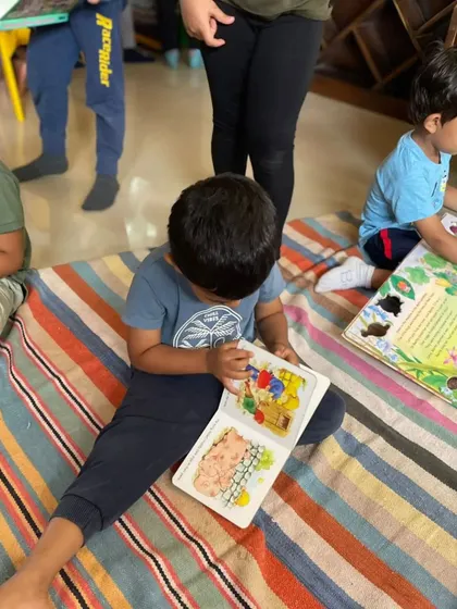 A young boy sits on the floor, deeply engrossed in a picture book. Our colorful striped mat provides a comfortable and inviting space for floor reading.