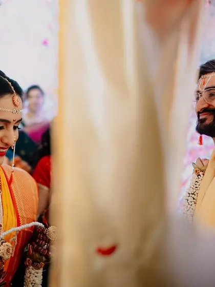 A beautiful, soft-focus shot of the couple during the wedding ceremony. The frame is captured through a gap, creating a sense of intimacy and focusing on their happy expressions.