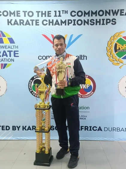An athlete showcasing his trophies and medals from the 11th Commonwealth Karate Championship in Durban, South Africa. This is the result of a 23-year journey of dedication to the sport.