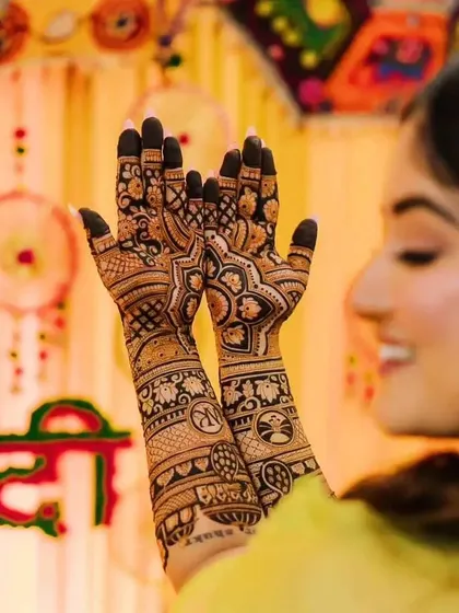 A beautiful shot of a bride holding up her hands, showing the back design with personalized initials and traditional patterns.