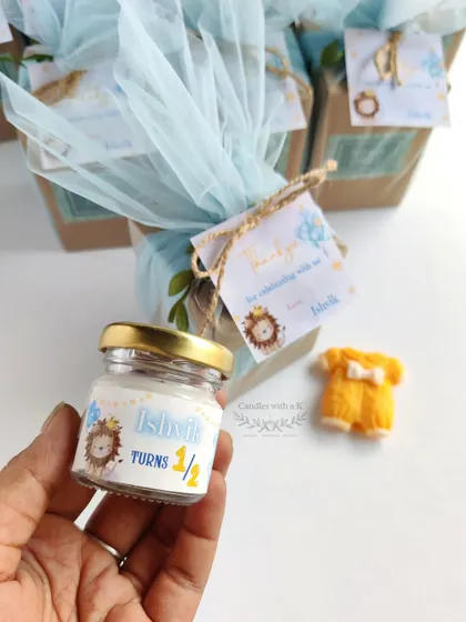 Holding the personalized mini jar candle for Ishvik's half-birthday, showing the custom lion-themed sticker.
