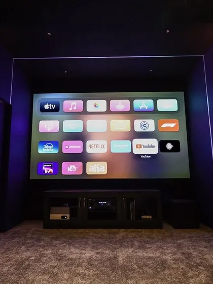 The Apple TV interface is displayed on the screen, showing that this compact theater is fully equipped with modern smart technology for easy access to content.
