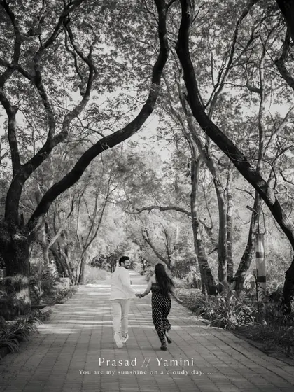 A beautiful black and white photo of the couple walking down a tree-lined path, capturing a feeling of journey and togetherness in their pre-wedding story.