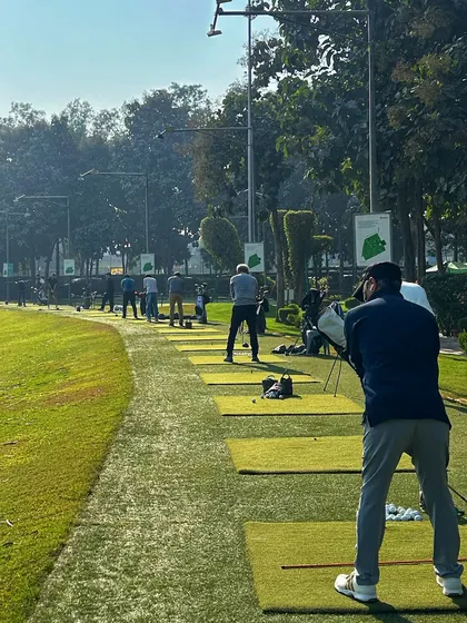 A view from behind a golfer, looking down the long line of bays on a clear day.