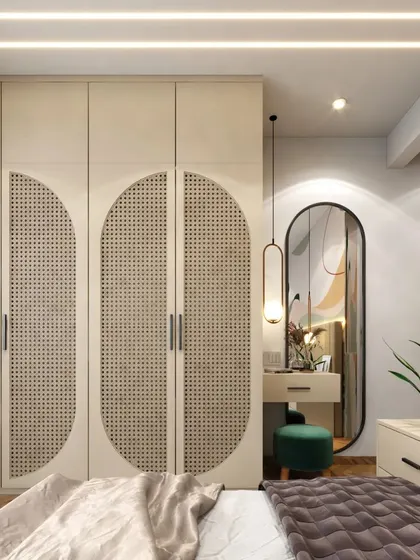 A bedroom with a bohemian touch, featuring a wardrobe with cane-paneled doors and a simple vanity table with a modern arched mirror.